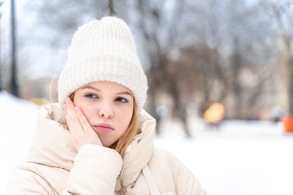 woman holding her jaw outside in the snow